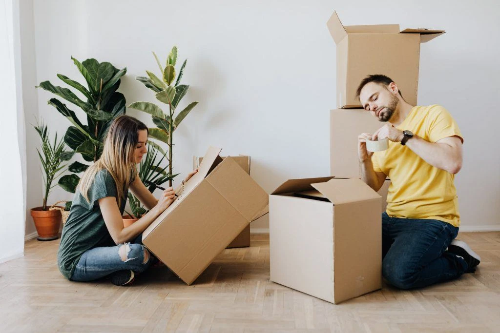 ein pärchen, dass umzugskartons packt und beschriftet